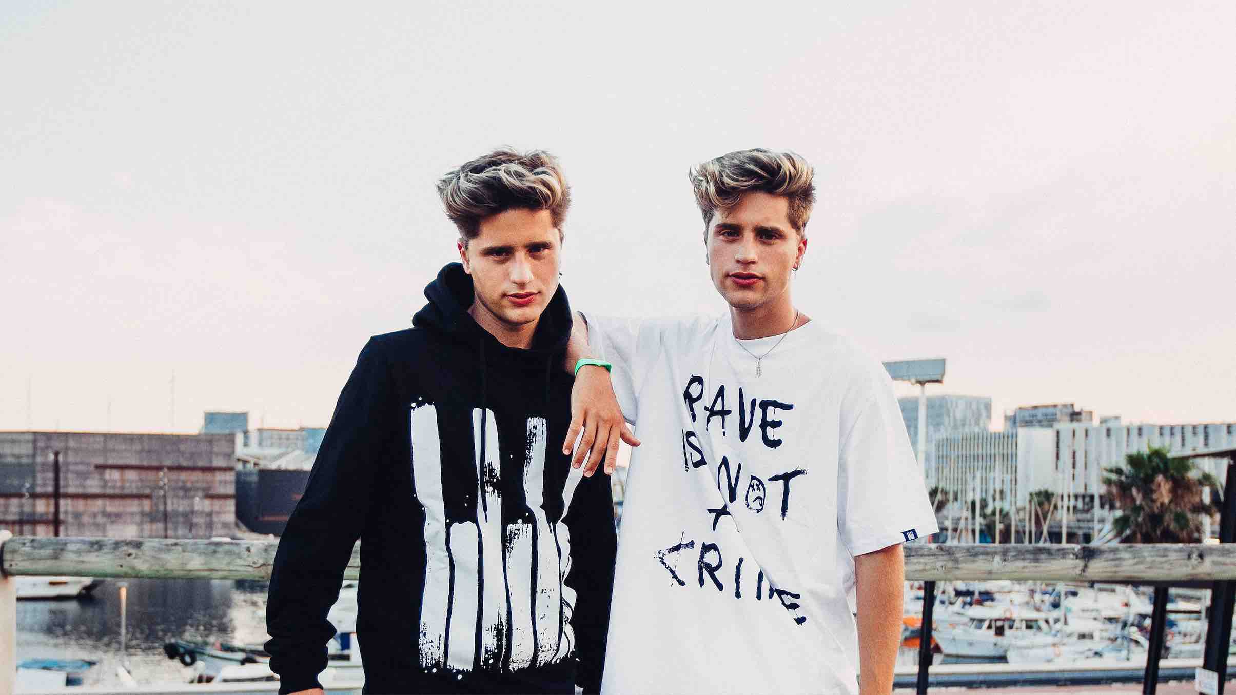 Banner Martinez Twins wearing Rave Culture Classic Emblem Hoodie and Rave Is Not A Crime T-Shirt at Barcelona Beach Festival (BBF)